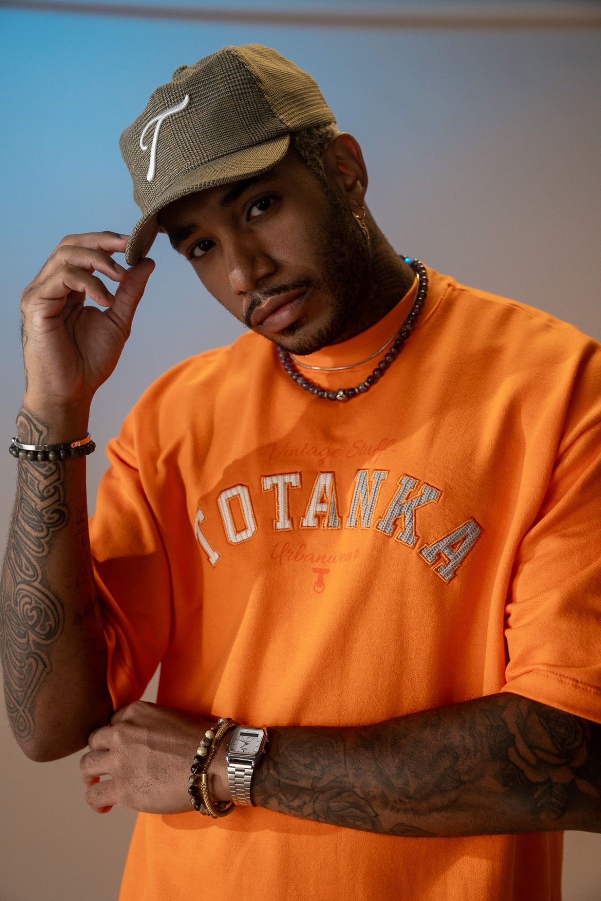 Camiseta laranja Totanka Vintage Stuff Urbanwear com aplique bordado, usada com boné xadrez